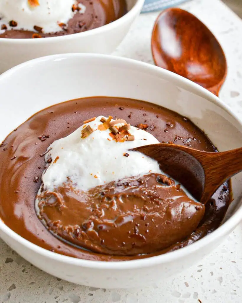 A close up view of chocolate pudding with whipped cream and chocolate shavings. 