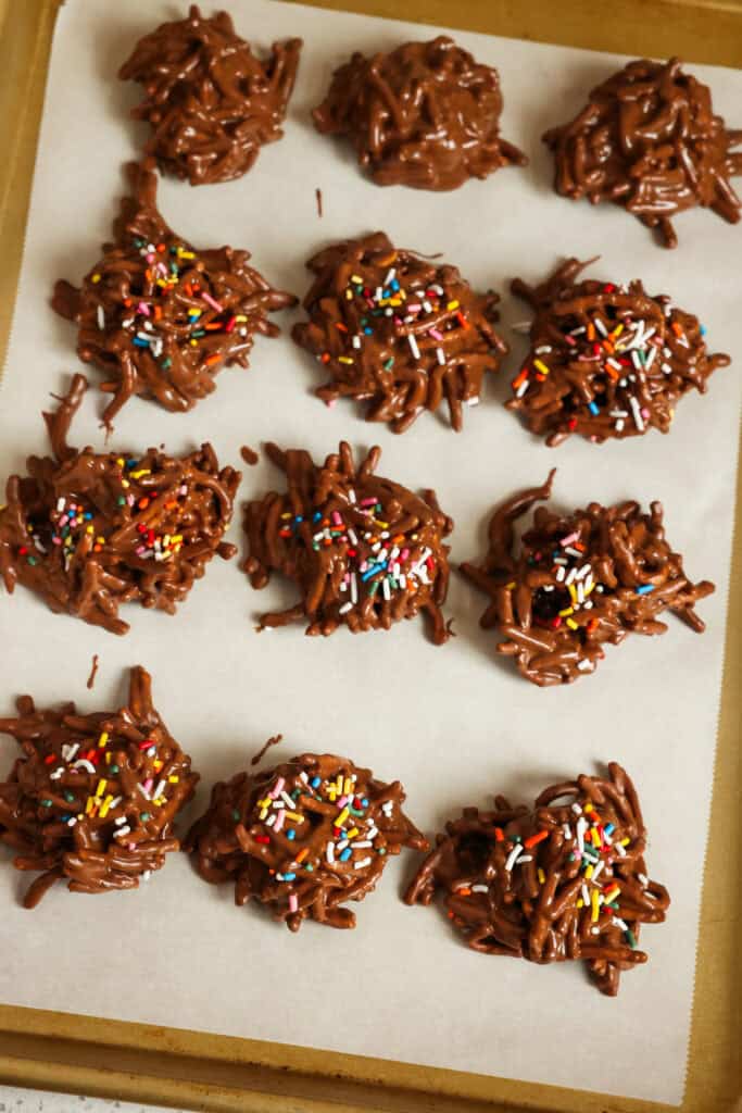 Chocolate haystack cookies with sprinkles on a baking sheet covered with parchment paper. 