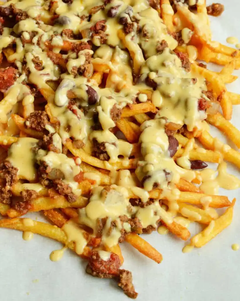 Scrumptious Chili Cheese Fries made with a hearty thick beef chili and topped with a lusciously creamy cheddar cheese sauce. 