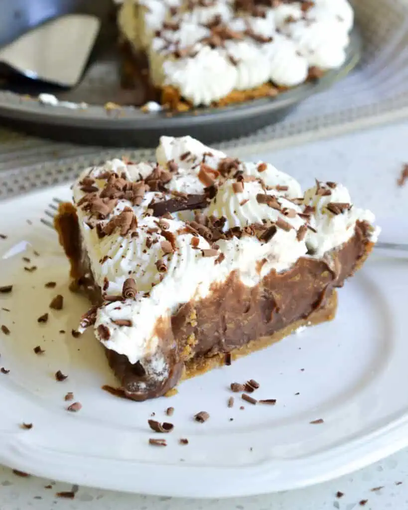 A piece of chocolate cream pie with whipped cream and chocolate shavings. 