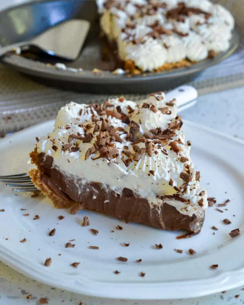 A piece of chocolate cream on a single serrving plate with a fork. 