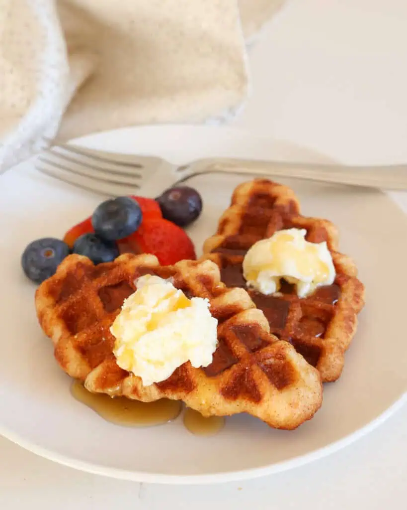 Two croffles on a plate with butter, maple syrup, and fresh berries. 