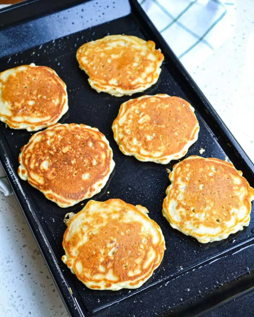 Golden brown oatmeal pancakes on a griddle. 