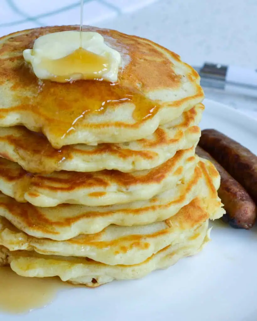 A close up view of oatmeal pancakes on a plate with pork sausage links. 