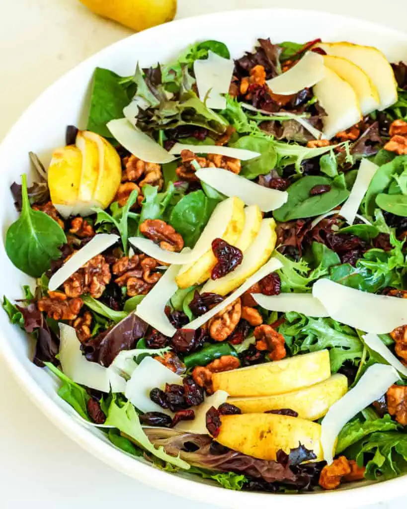 This Pear Salad combines candied walnuts, mixed greens, fresh pears, dried cranberries, and shaved Parmesan cheese, all drizzled with a homemade balsamic vinaigrette.