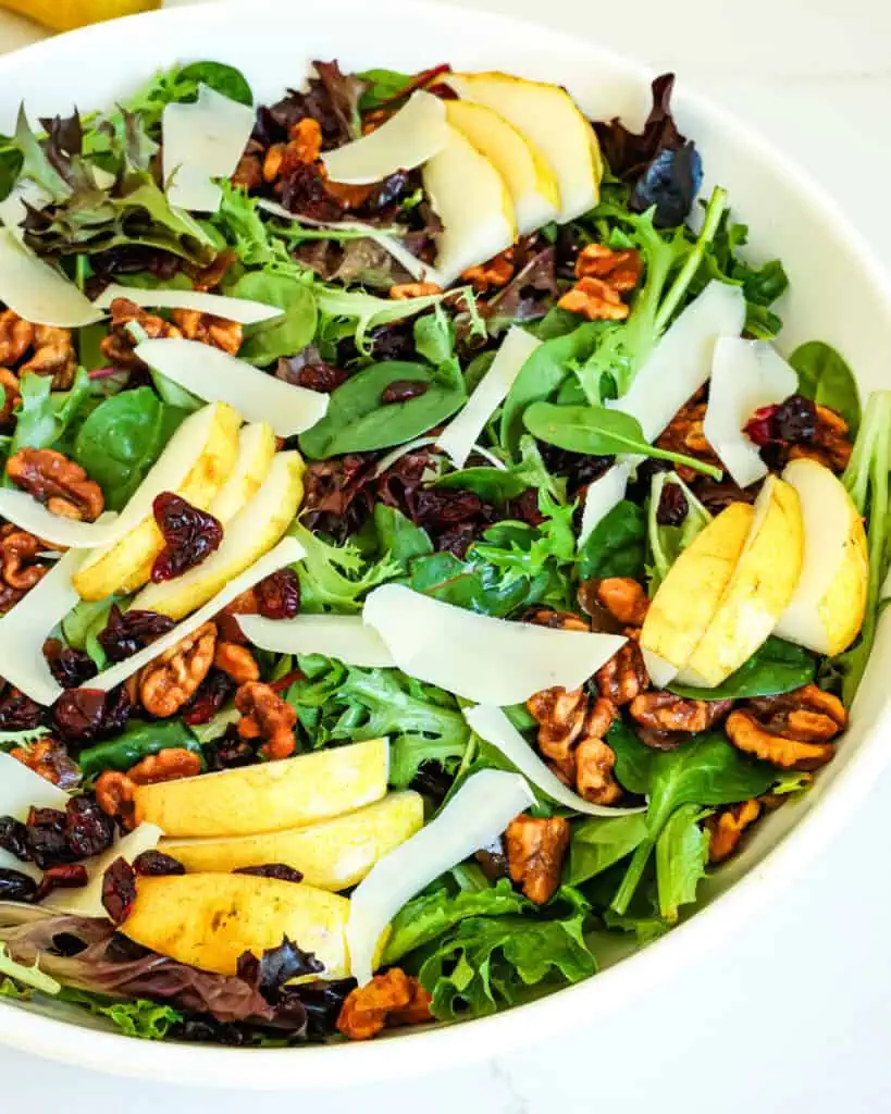 This Pear Salad combines candied walnuts, mixed greens, fresh pears, dried cranberries, and shaved Parmesan cheese, all drizzled with a homemade balsamic vinaigrette. 