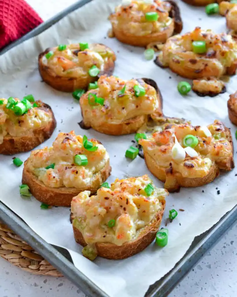 Shrimp toast on a parchment covered baking sheet. 