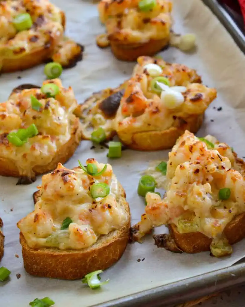 A close up view of shrimp toast on a parchment covered baking sheet. 
