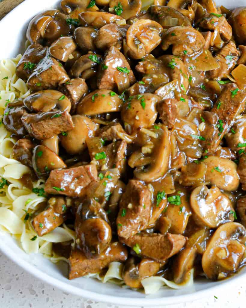 Beef and mushrooms in gravy over noodles and sprinkled with parsley. 