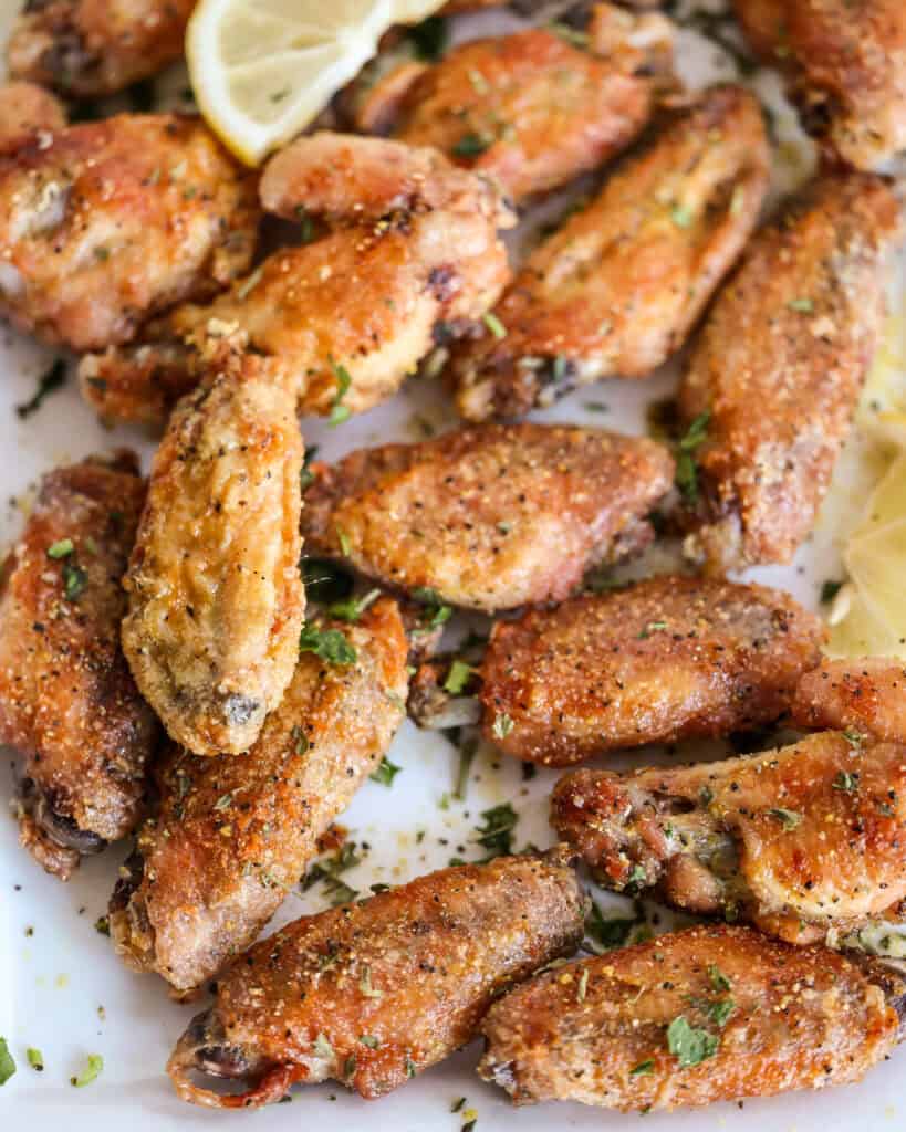 When baking the wings in the oven, use parchment paper on the sheet pan for even baking, extra crispy wings, and easy cleanup. Make sure the parchment paper is rated for at least 400 degrees.
You can melt the butter in the microwave to save on dishwashing time, but I prefer to melt it over the stovetop.
Sprinkle the wings with a little more lemon pepper or lemon zest right after smothering them in the butter mixture and before serving.
Garnish the platter with fresh chopped parsley and lemon slices.
