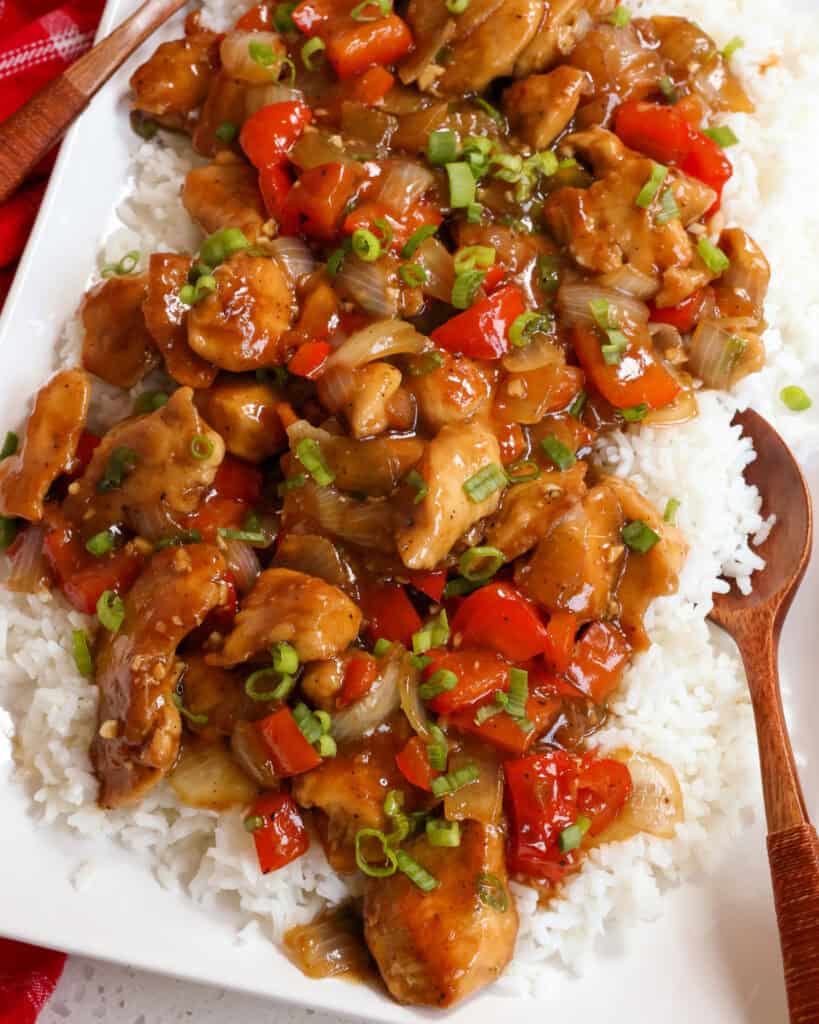 Pepper chicken over white rice on a serving platter. 