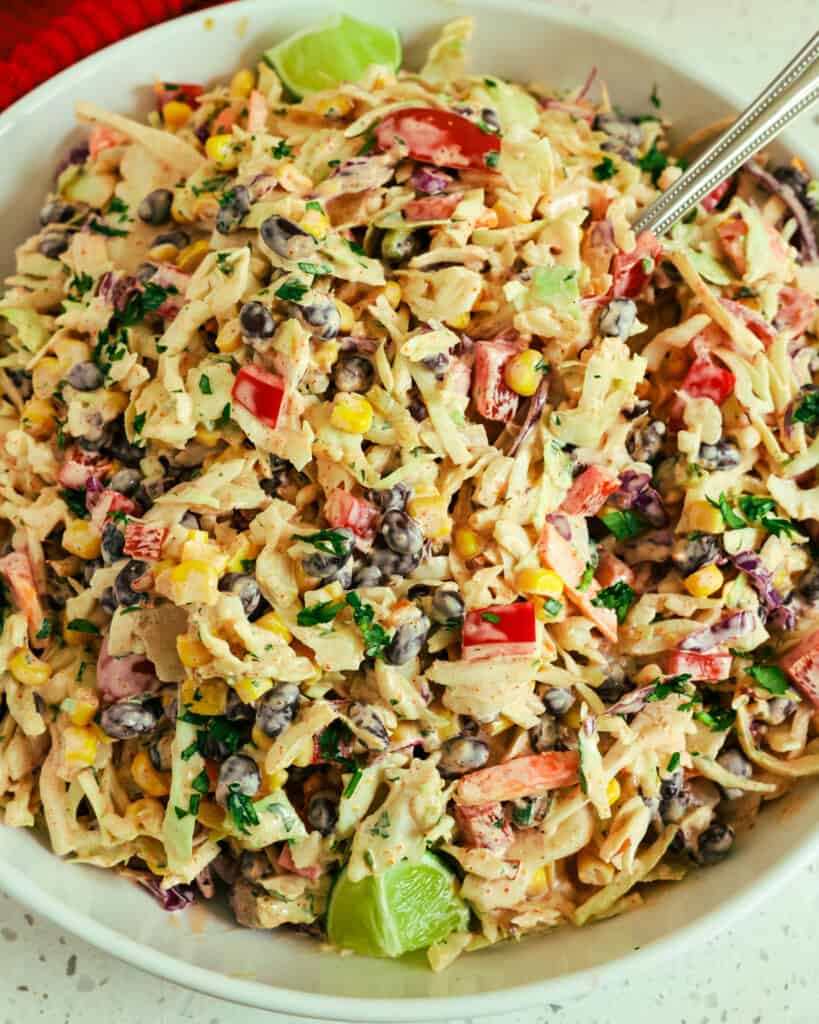 A bowl full of Mexican coleslaw with a spoon in it. 