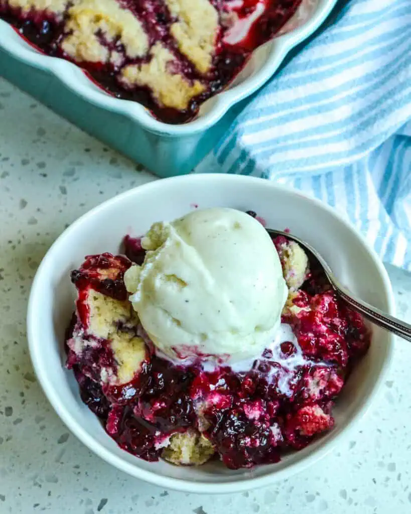 Blackberry cobbler and a scoop of ice cream in a small bowl. 