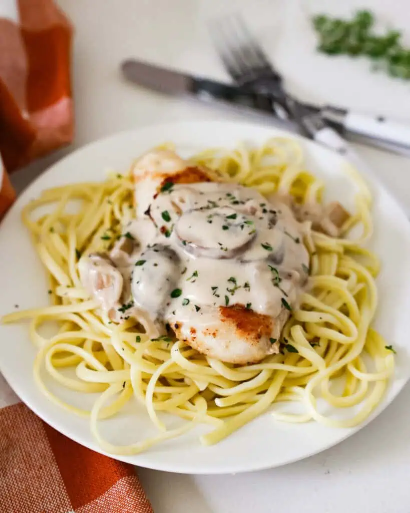 A single serving of chicken marsala over pasta. 