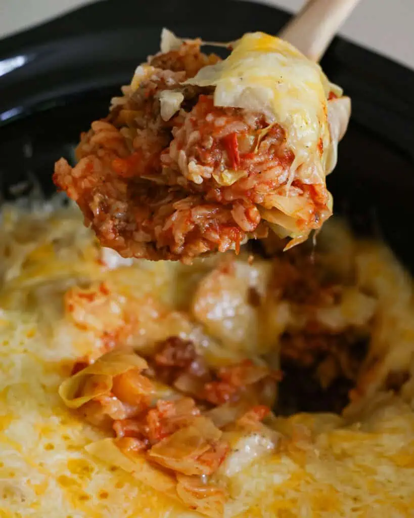A large spoon filled with crock pot cabbage roll casserole. 