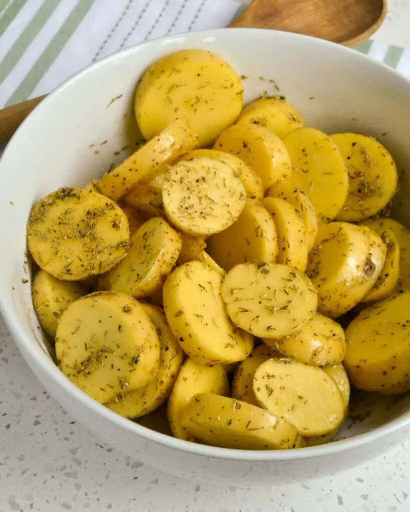 Raw Yukon Gold Potatoes mixed with oil and dried herbs