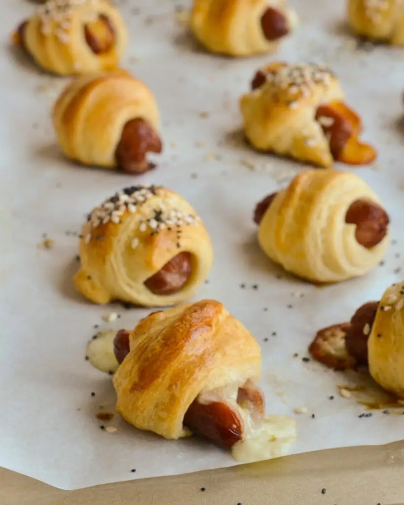 Mini pigs in a blanket on a baking sheet covered with parchment paper. 