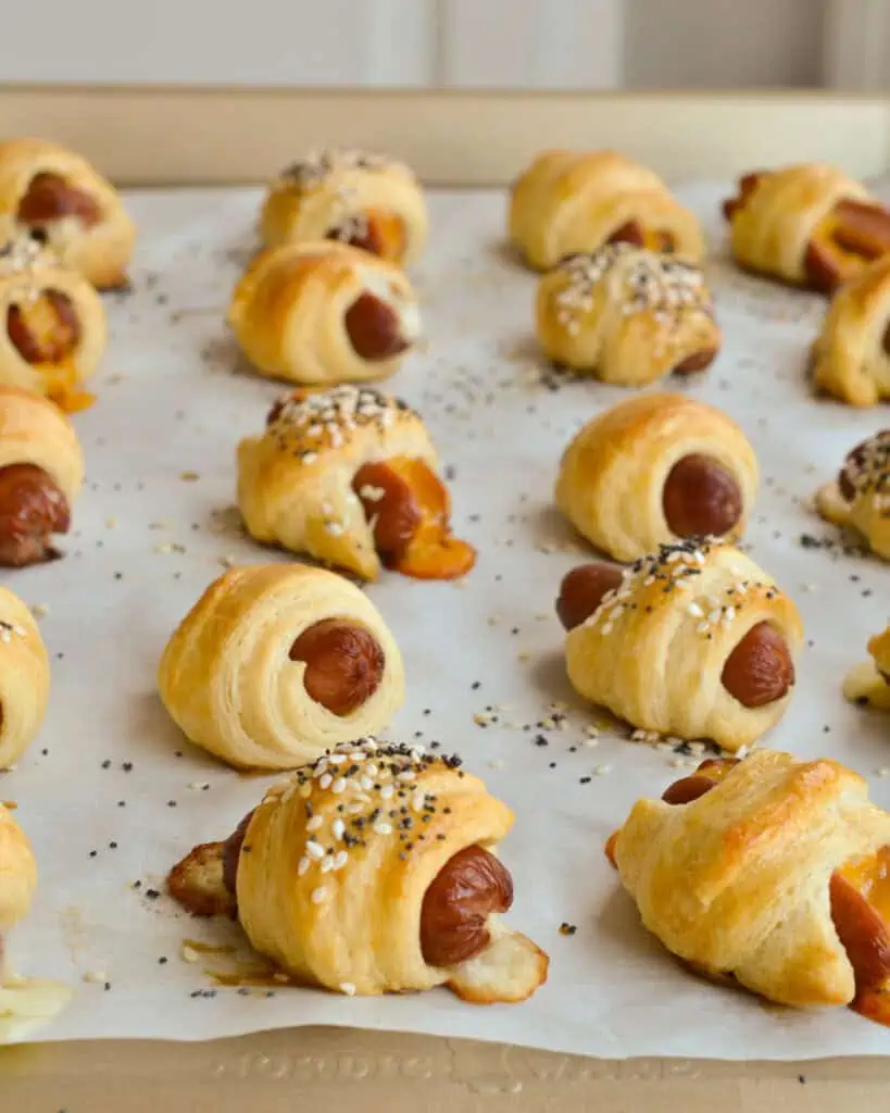 Fresh baked mini pigs in a blanket  on a baking sheet covered with parchment paper. 