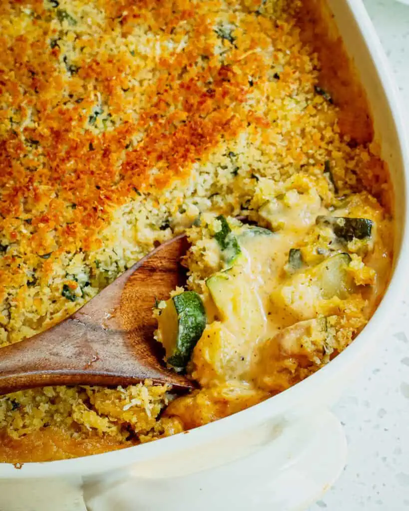 A fresh zucchini casserole with sautéed onions and garlic in a creamy cheese sauce topped with buttery Parmesan Panko breadcrumbs.