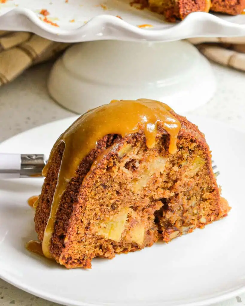 A single slice of apple cake on a plate with a fork. 