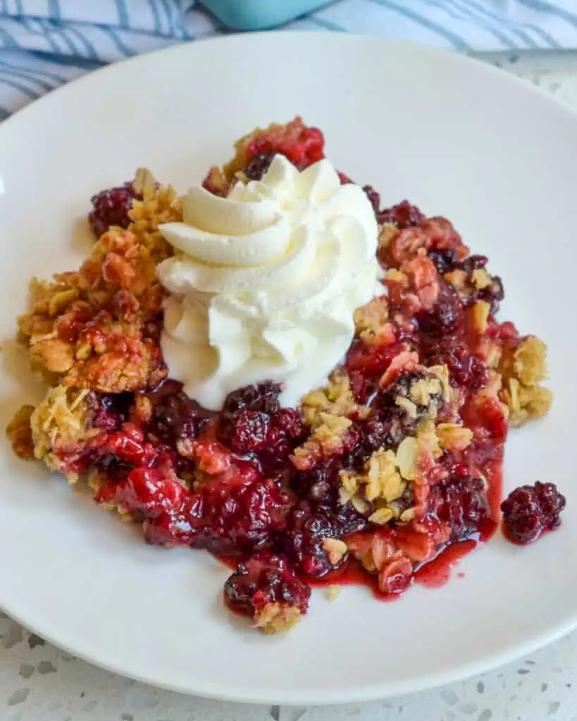 Blackberry Crisp on a plate with whipped cream. 