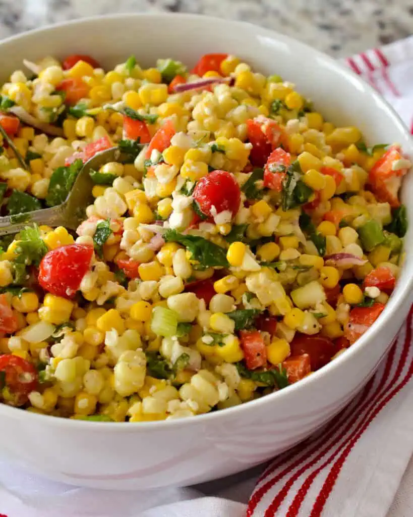 This delectable corn salad brings it all together with fresh corn, sweet red bell peppers, sun-ripened tomatoes, cilantro, minced jalapeno, chopped scallions, and feta cheese, all in a lightly sweetened lime vinaigrette.