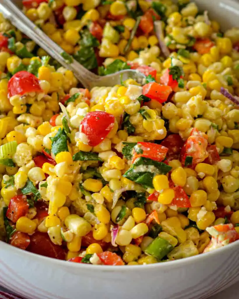 A close up of corn salad in a bowl over a kitchen towel. 