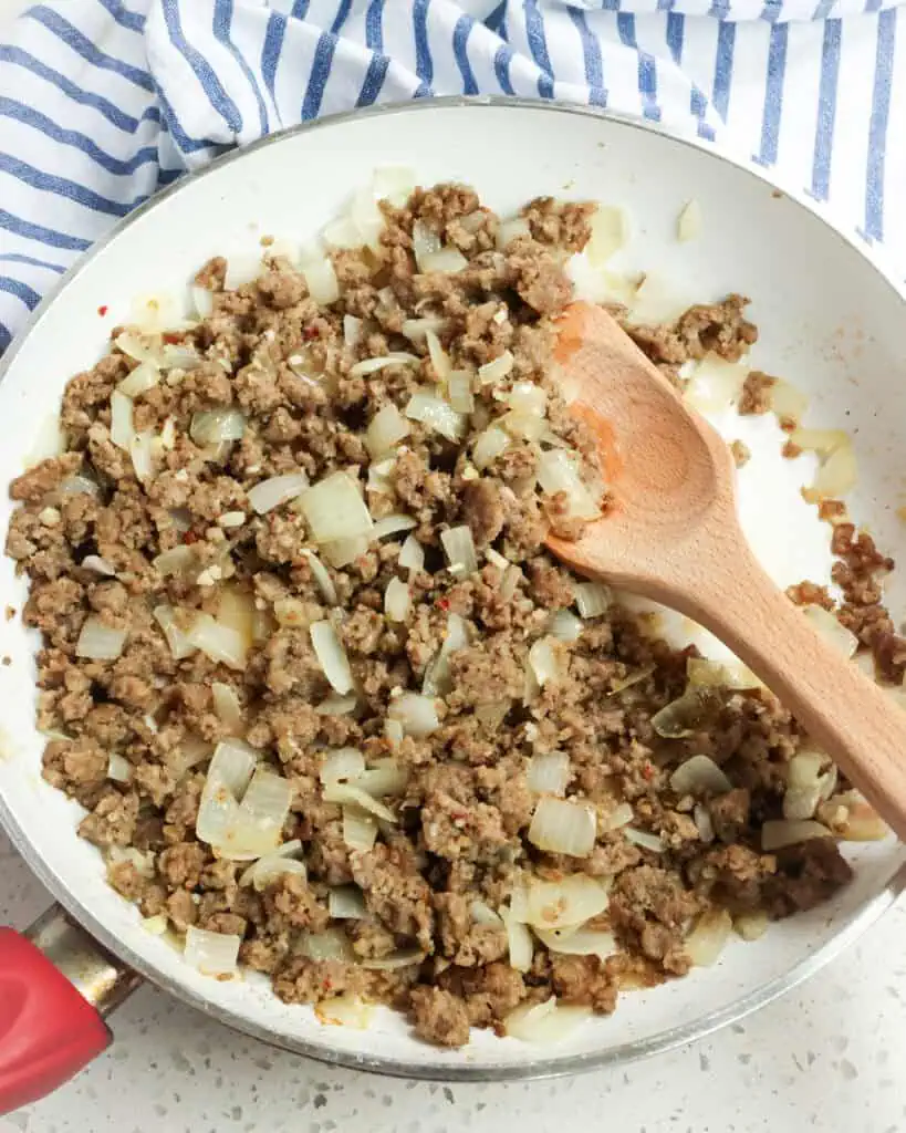 Sausage, onion, and garlic cooked in a skillet. 