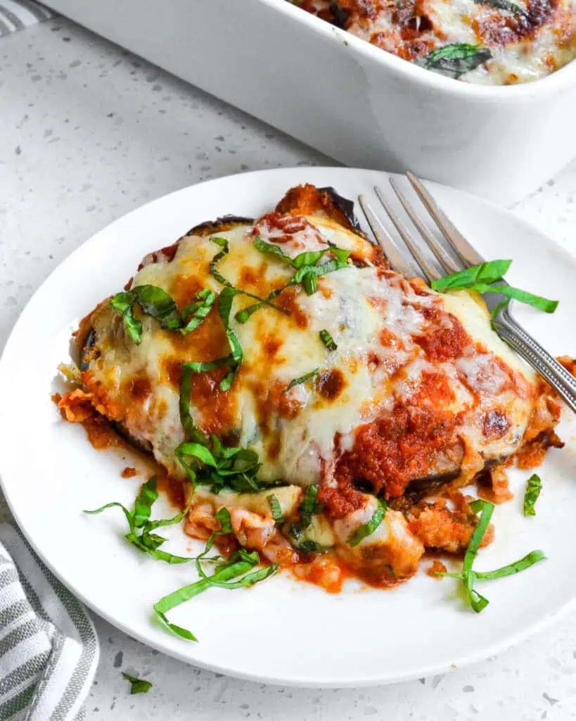 An individual plate with eggplant parmesan and a fork. 