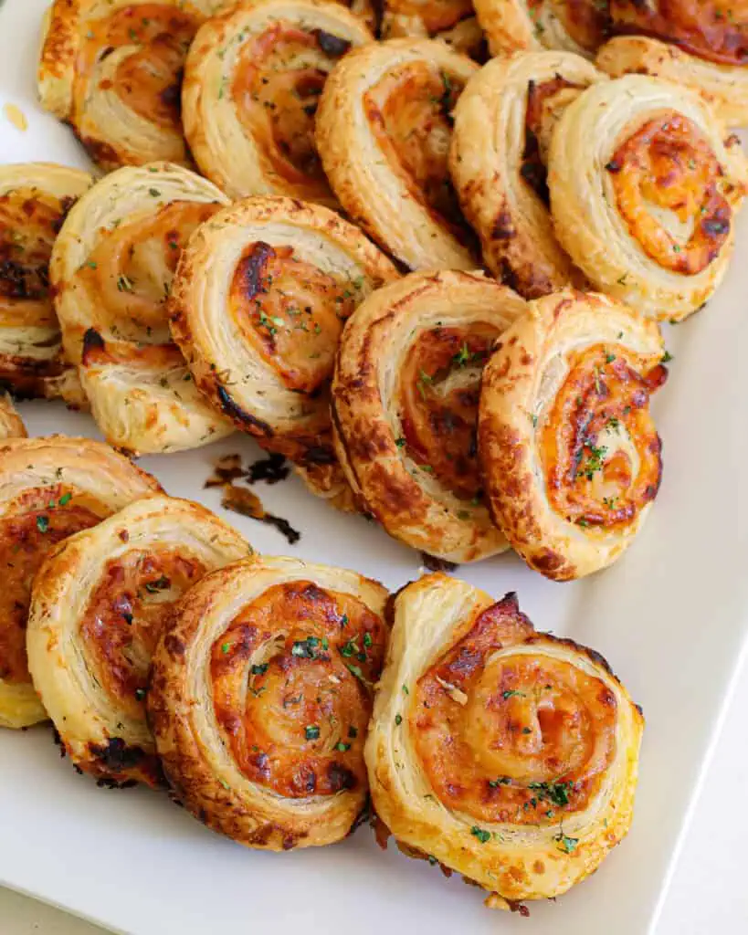 Ham and cheese puff pastry pinhweels on a serving platter. 