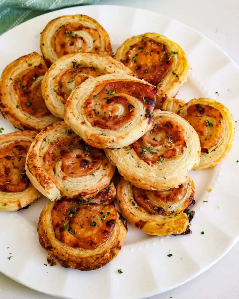 Freshly baked ham and cheese pinhweels on a large plate. 