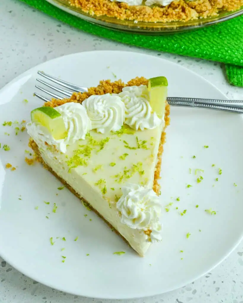 A slice of key lime pie on a plate with a fork. 