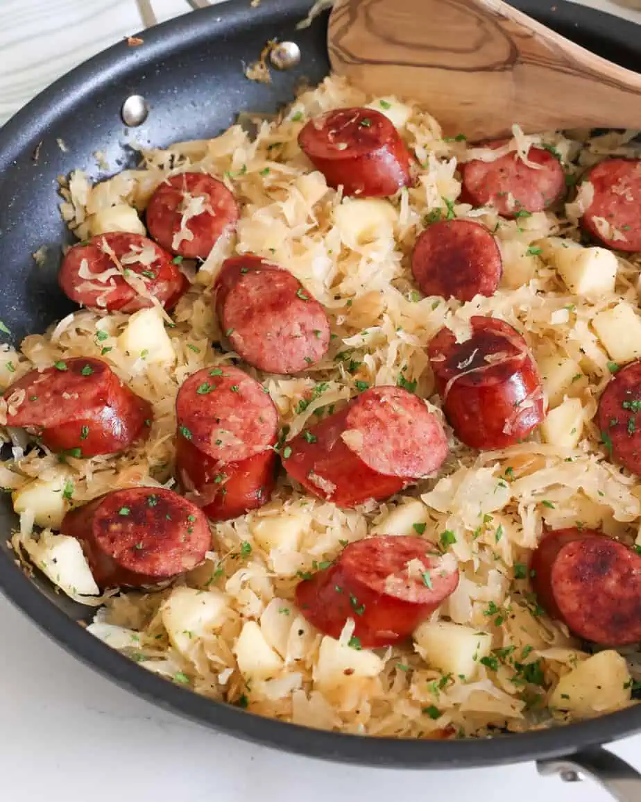 Polish sausage, sauerkraut and apples in a skillet. 