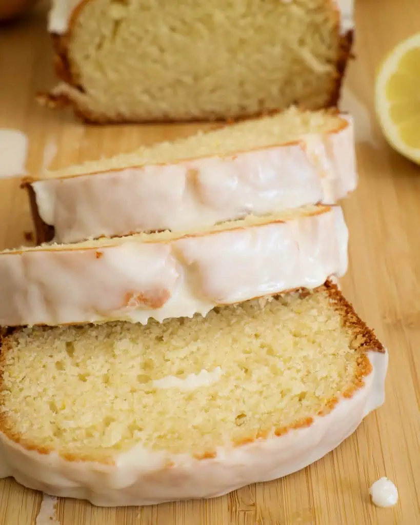 A close up view of three slices of glazed lemon bread. 