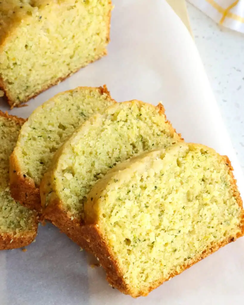 Slices of lemon zucchini bread on parchment paper on a cutting board