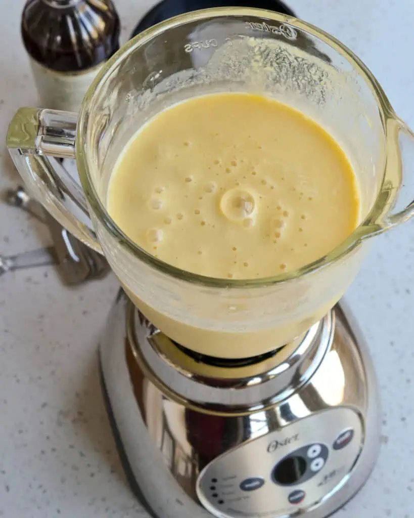 A blender full of a creamy frosty orange drink