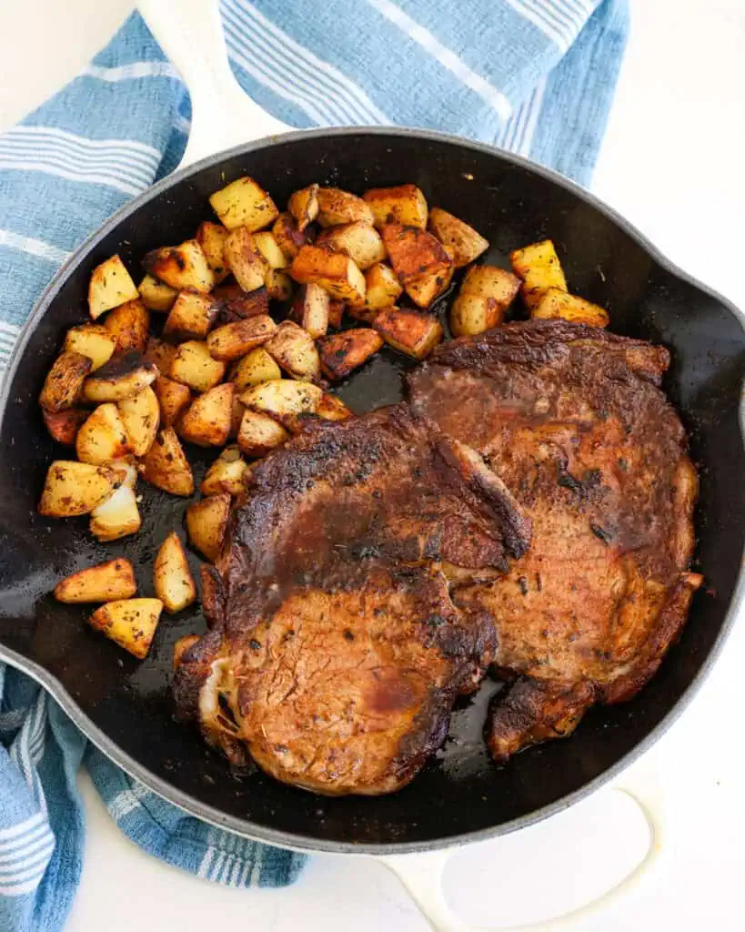 Pan fried potatoes and seared ribeyes in a large skillet. 