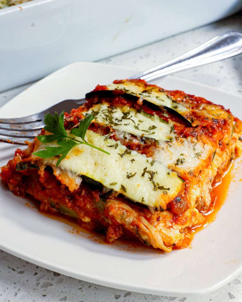 A pierce of zucchini lasagna on a plate with a fork. 