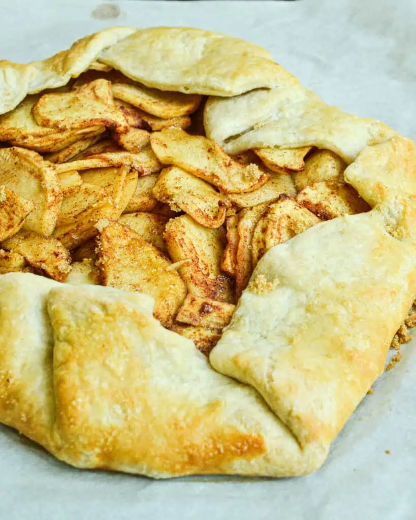 A baked apple galette on a baking sheet covered with parchment paper. 