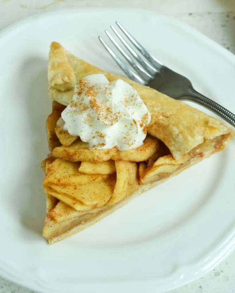 Apple galette with a little bit of whipped cream on top and a dash of cinnamon. 