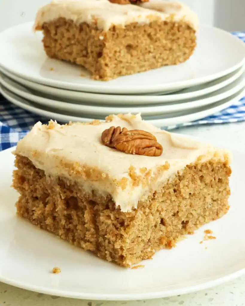 Applesauce cake on a plate with another piece of appleauce cake on a plate in the background