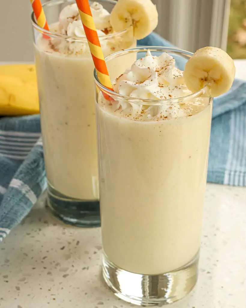 Two banana smoothies with a dash of cinammon and whipped cream. 