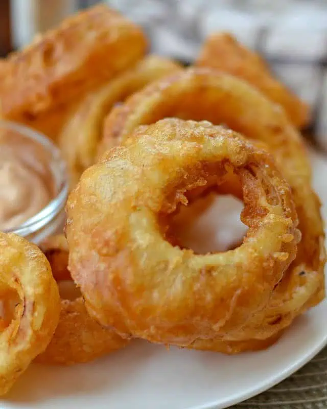Crispy golden beer battered onion rings on a plate with sauce, 