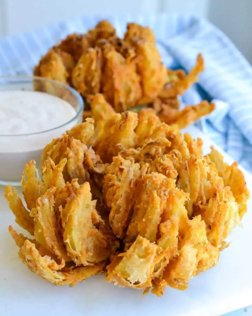 Two blooming onions with sauce on a tray. 