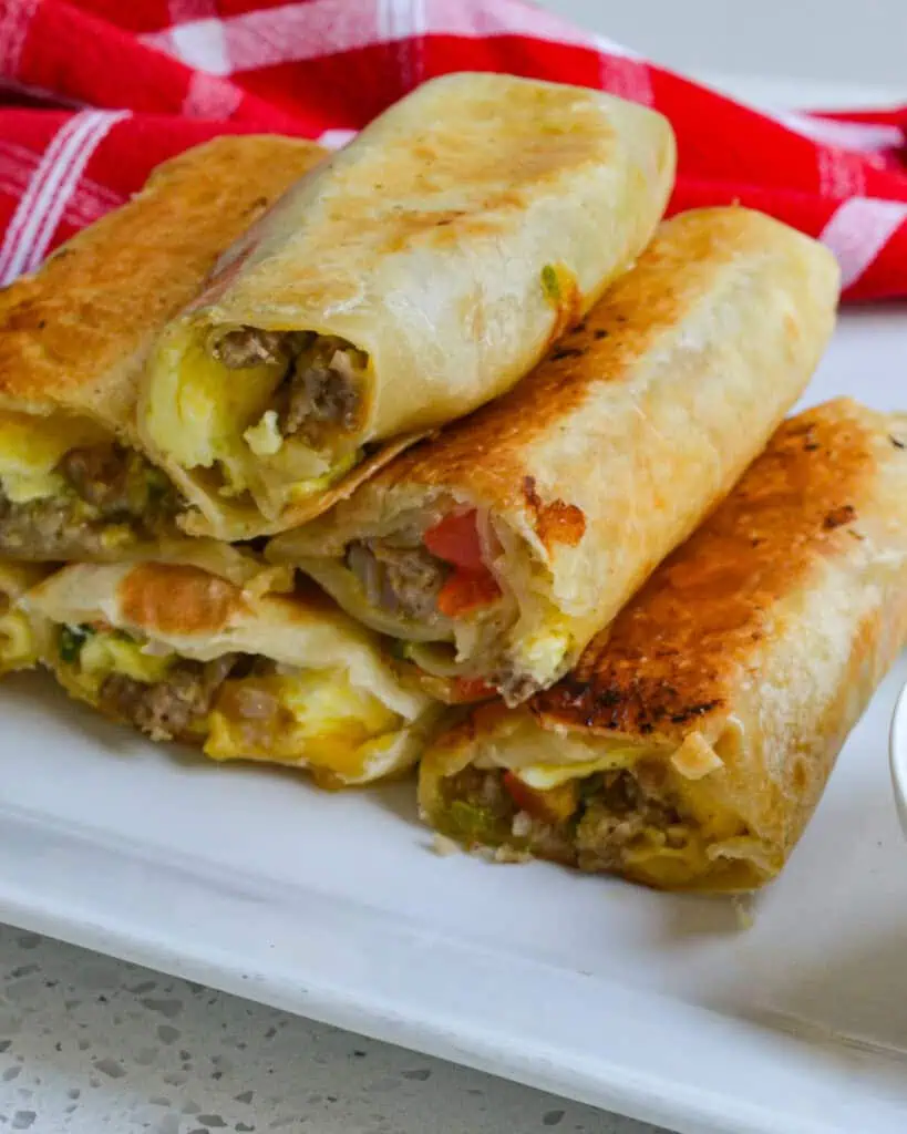 Breakfast burritos stacked on a serving platter. 