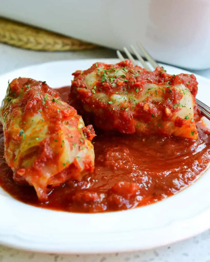 Two cabbage rolls on a plate with sauce. 