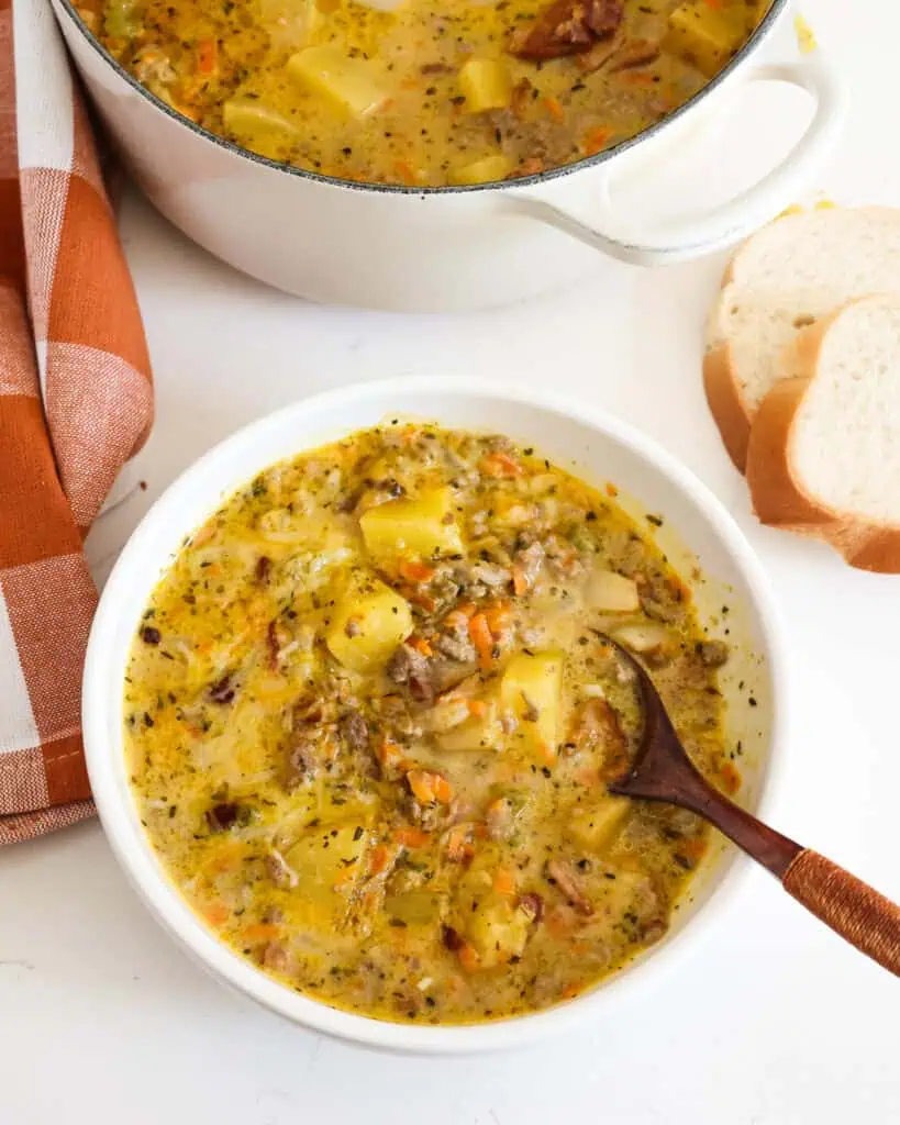 A bowl of cheese burge soup with poatoes, ground beef, and bacon. 