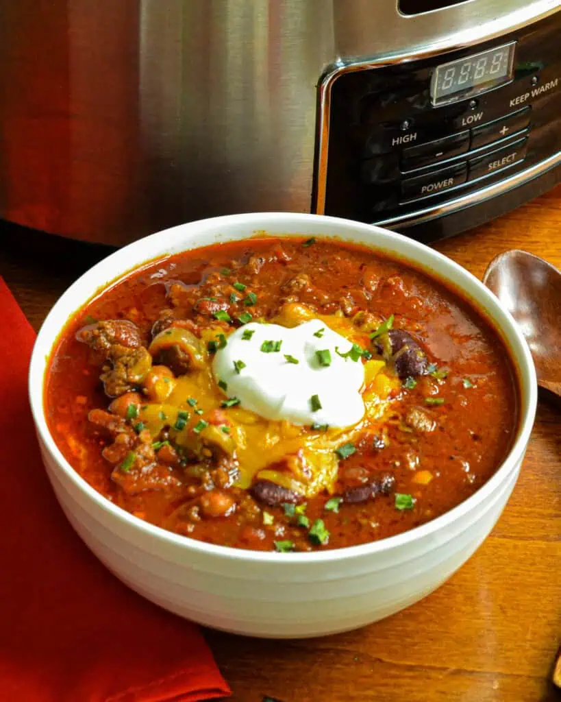 A crock and a bowl full of crock pot chili