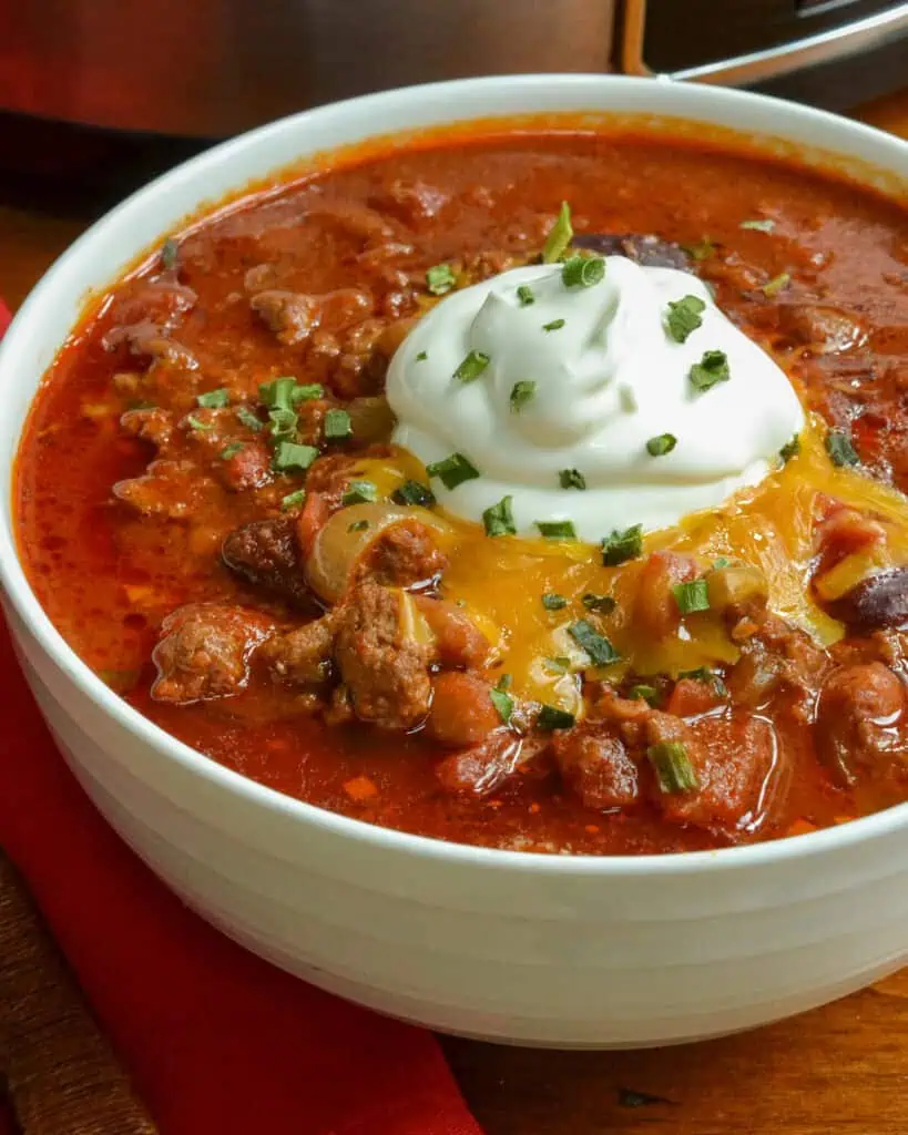 A bowl full of chili topped with sour cream and cheese. 