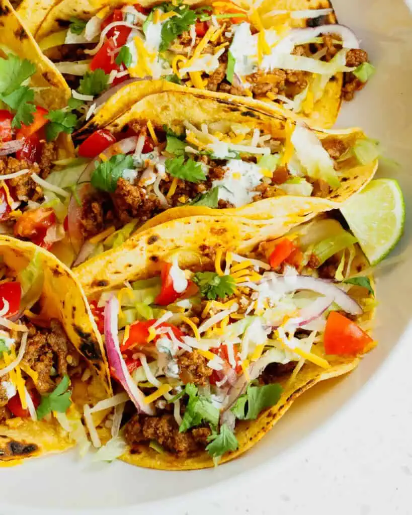 Ground beef tacos with all the fixings in blackened corn tortillas. 